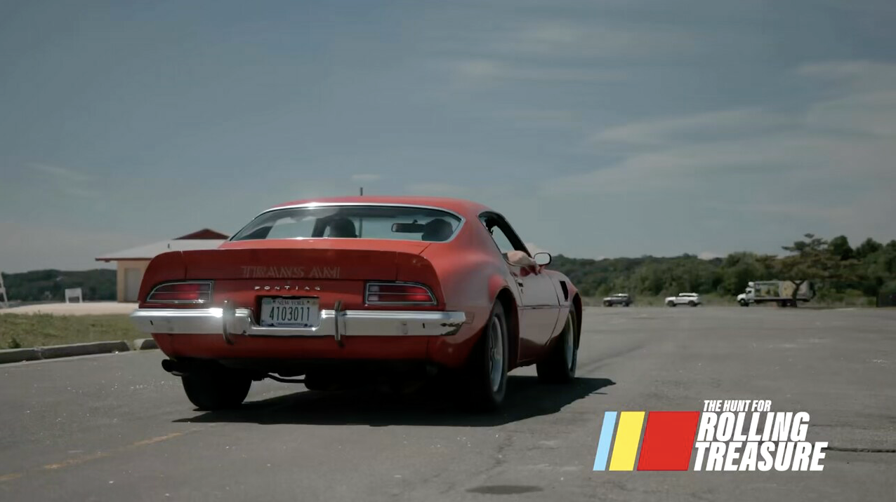 Red Pontiac Trans Am driving with the Rolling Treasure logo